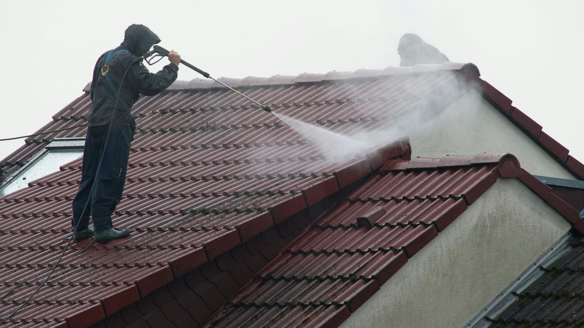 Arbeiter reinigen das Dach eines Hauses