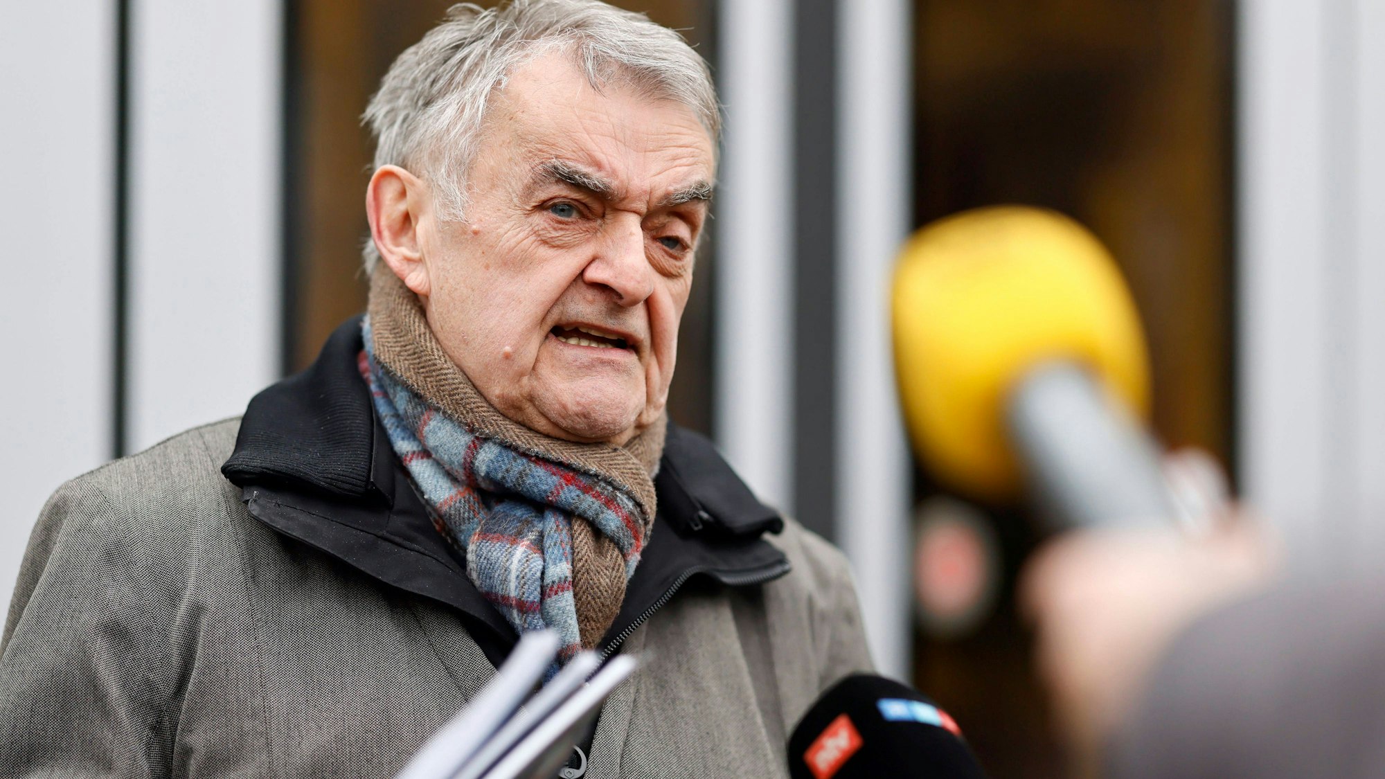 Mann mit Schal spricht in Mikrofone