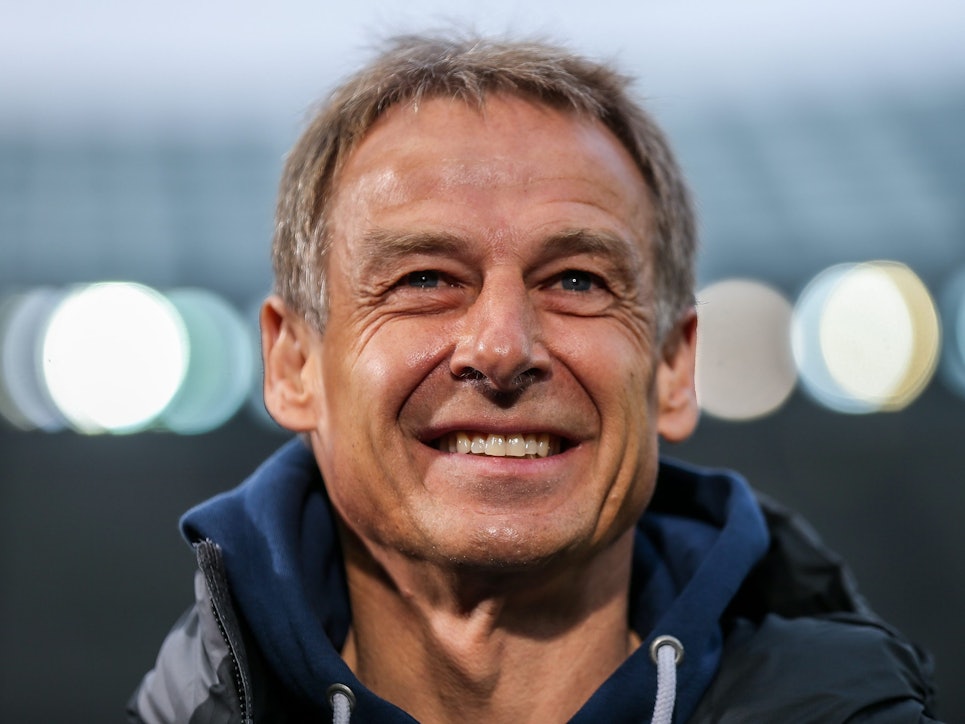 Jürgen Klinsmann lacht und schaut über die Kamera hinweg.