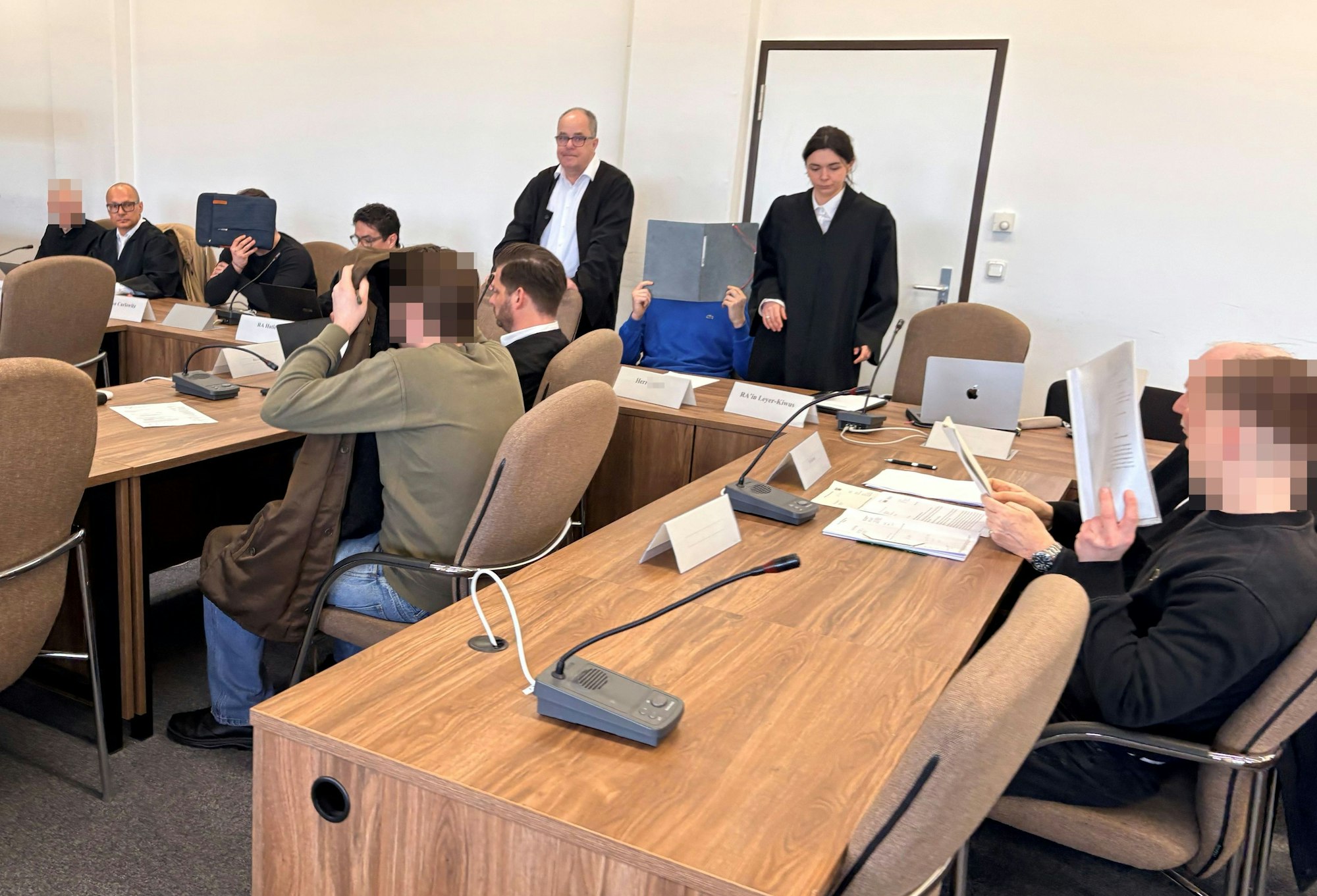 Die fünf Angeklagten mit ihren Verteidigerinnen beim Prozessauftakt in Saal 112 des Kölner Landgerichts