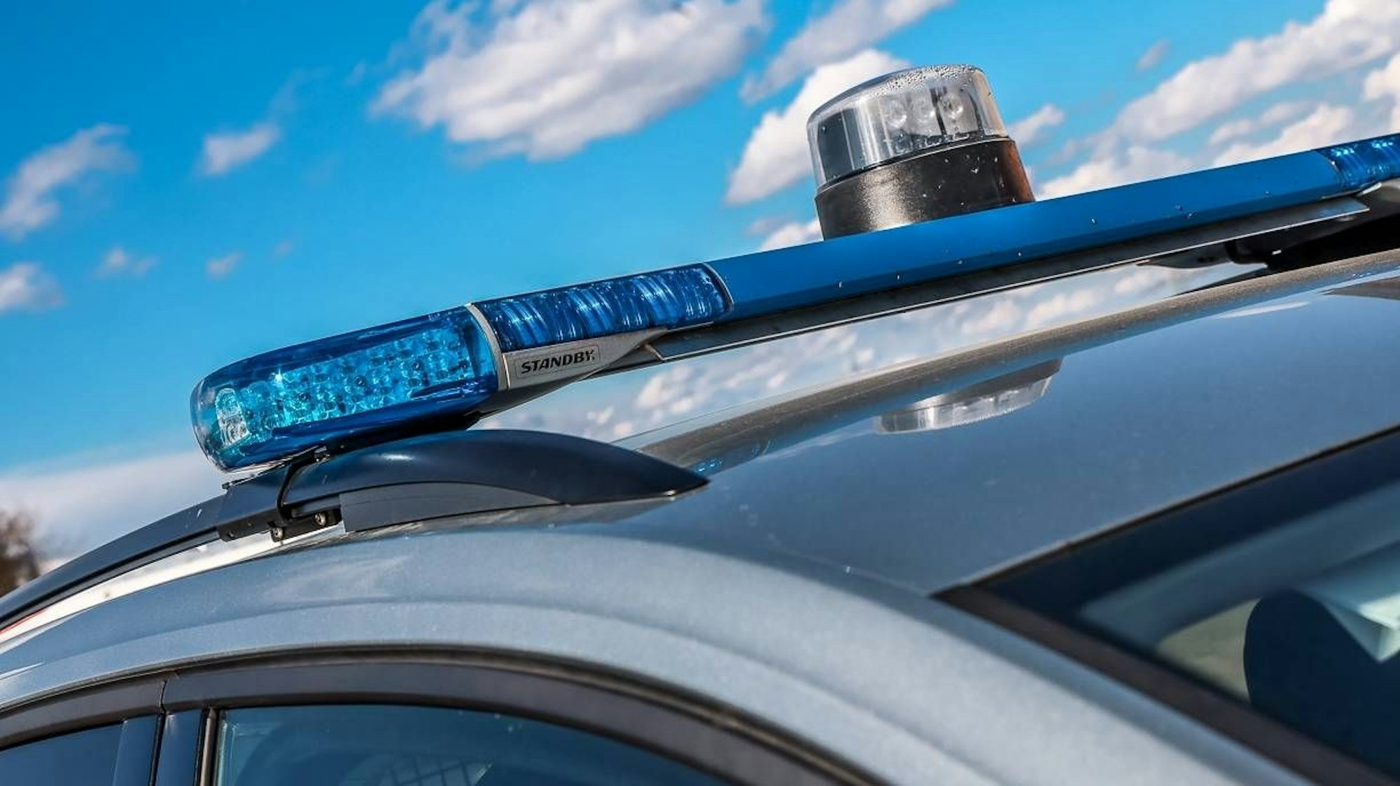Polizeiauto mit Blaulicht vor blauem Himmel