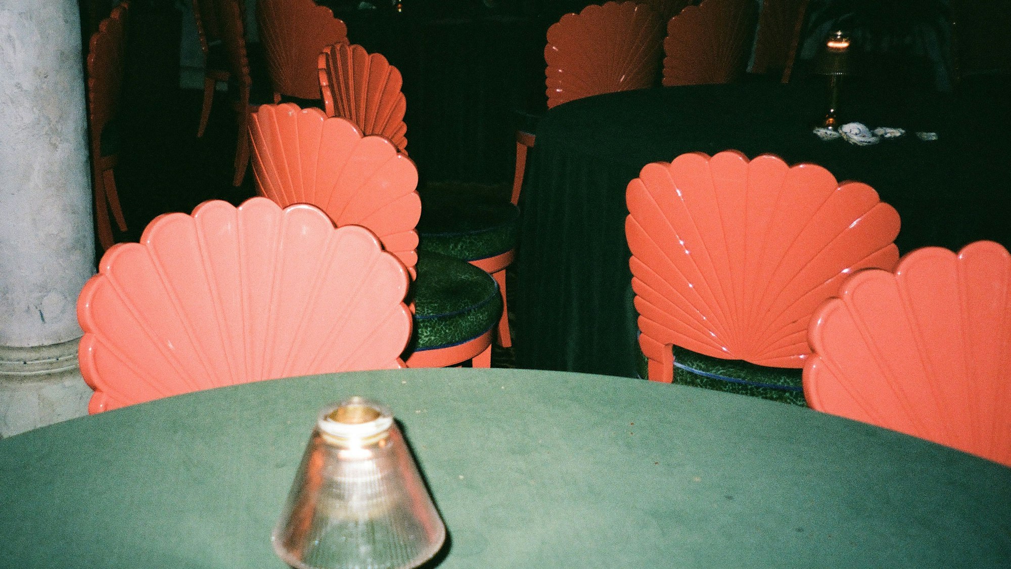 Korallenfarbene Muschelstühle und grüne Tische