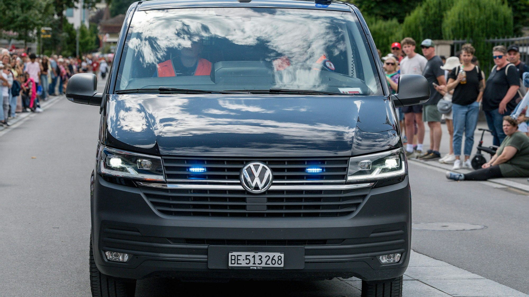 Polizeiauto mit Blaulicht und Menschen