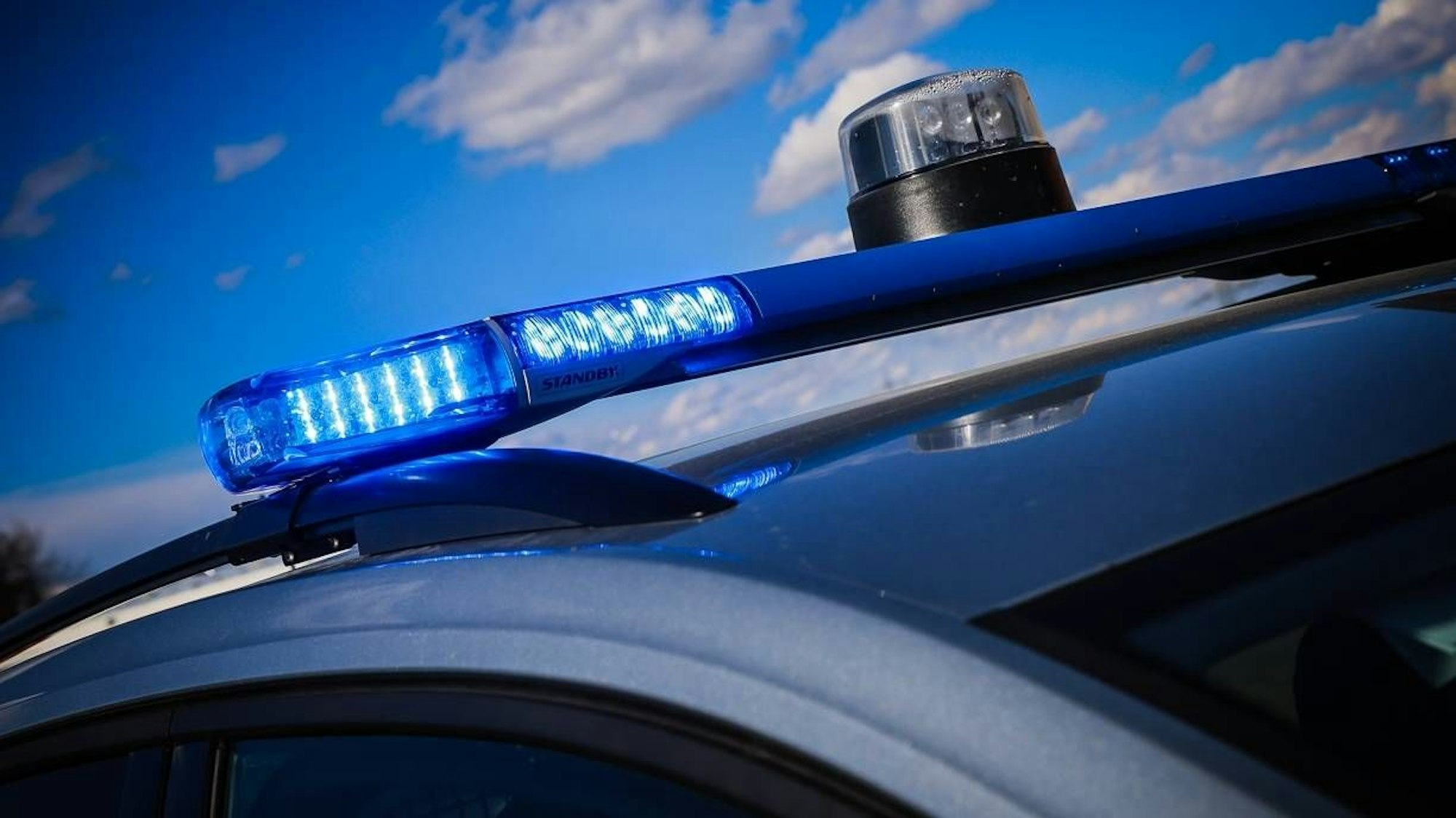 Polizeiwagen mit Blaulicht unter blauem Himmel