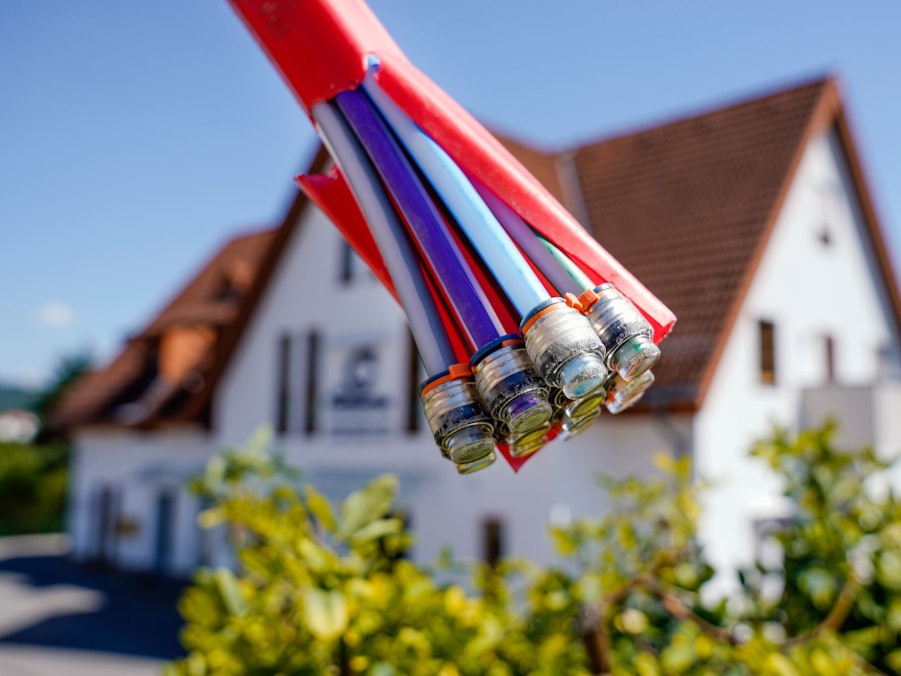 Bündel mit Umhüllungen für Glasfaserkabel vor einem Wohnhaus