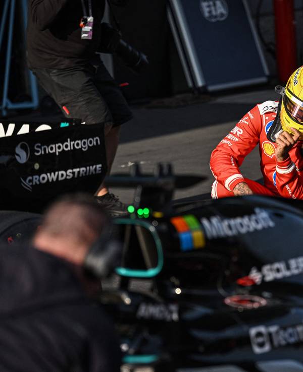 Lewis Hamilton schaut sich den Mercedes-Boliden in der Boxengasse aus der Nähe an.