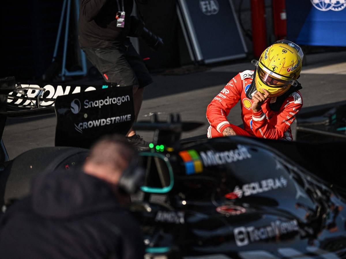 Lewis Hamilton schaut sich den Mercedes-Boliden in der Boxengasse aus der Nähe an.
