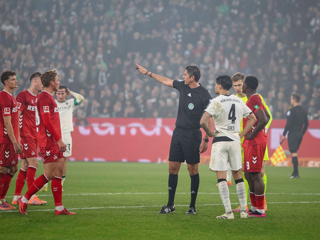 Deniz Aytekin gestikuliert, um ihn herum stehen Spieler von Gladbach und Köln.