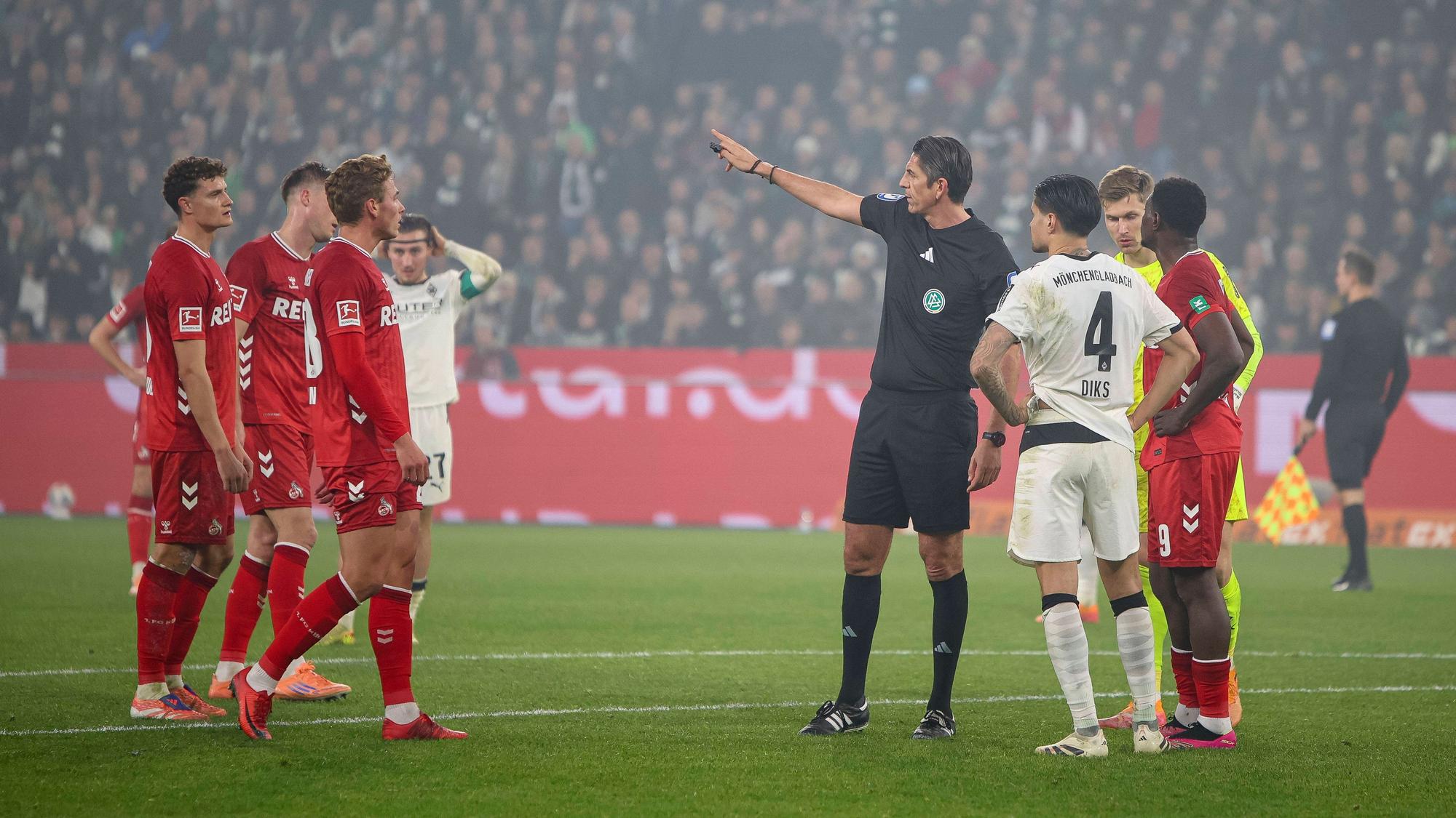 Deniz Aytekin gestikuliert, um ihn herum stehen Spieler von Gladbach und Köln.
