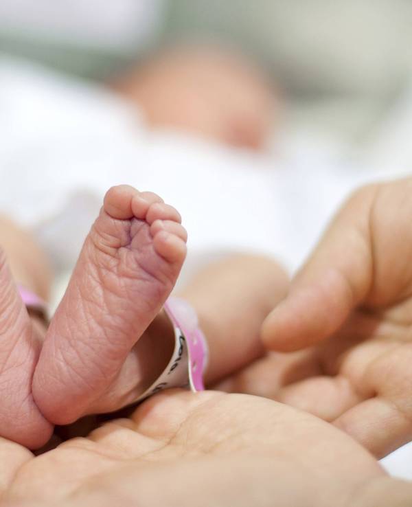 Vater hält Babyfüße des Neugeborenen