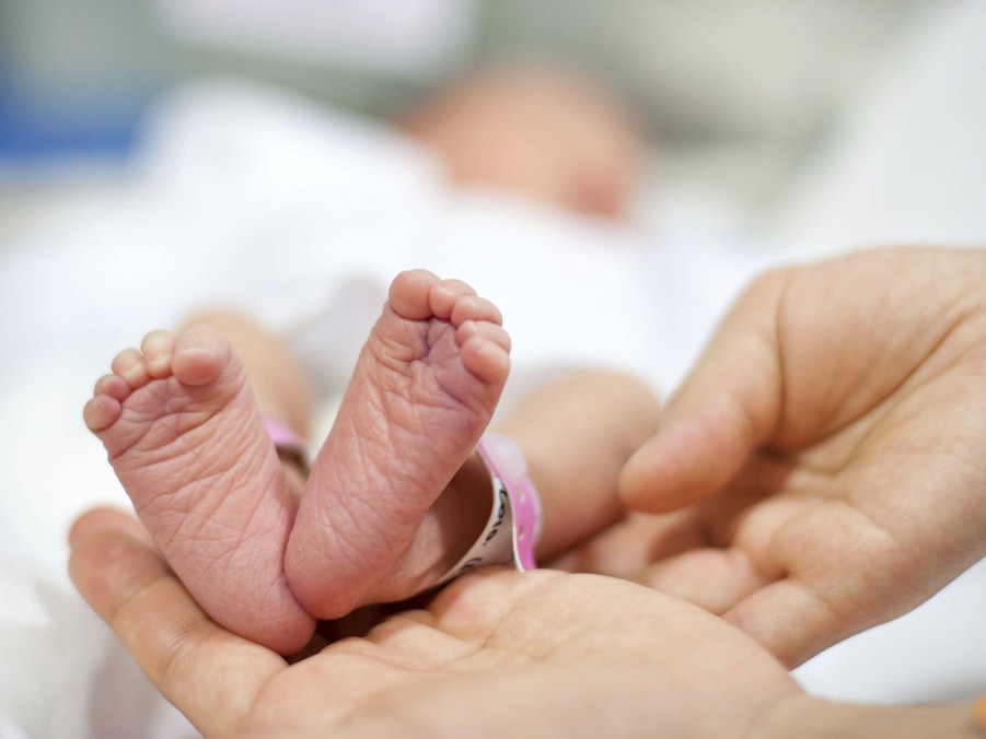 Vater hält Babyfüße des Neugeborenen