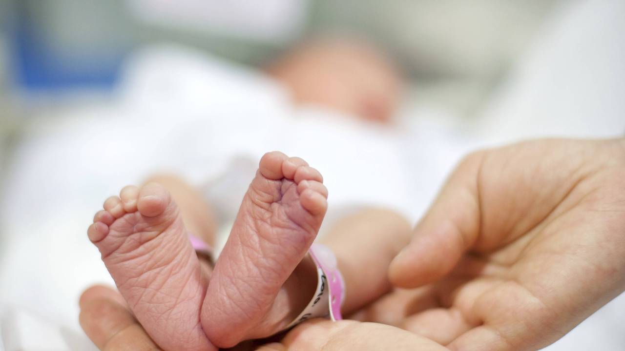 Vater hält Babyfüße des Neugeborenen