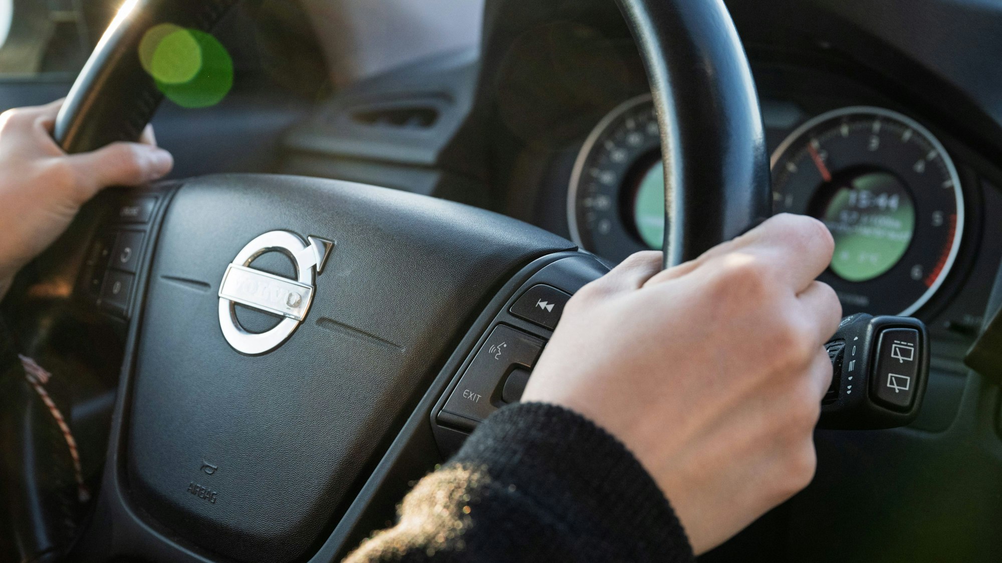 Hände am Lenkrad, Armaturen im Hintergrund
