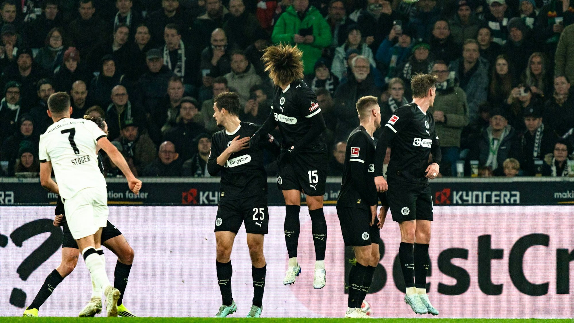 Kevin Stöger sowie zahlreiche Spiele des FC St. Pauli schauen dem Ball hinterher.