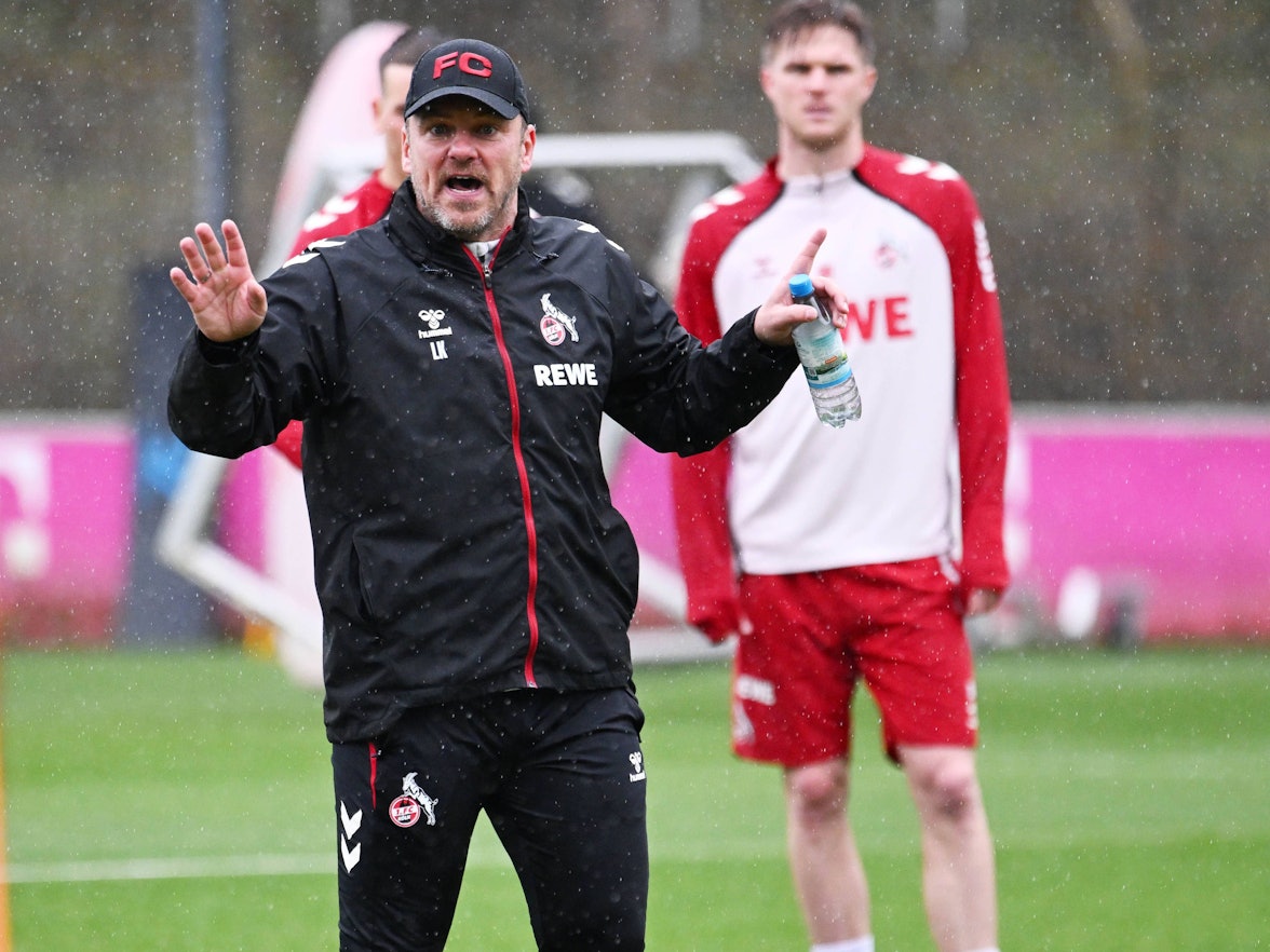 Kölns Trainer Lukas Kwasniok steht im Regen auf dem Trainingsplatz.