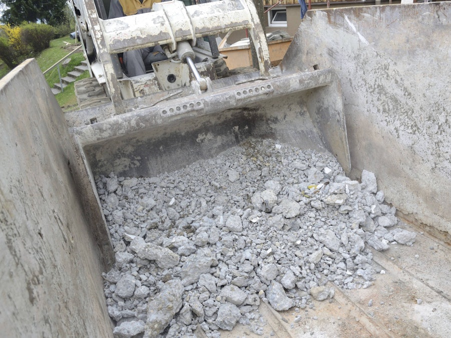 Bauschutt wird von Bagger in Container geschüttet