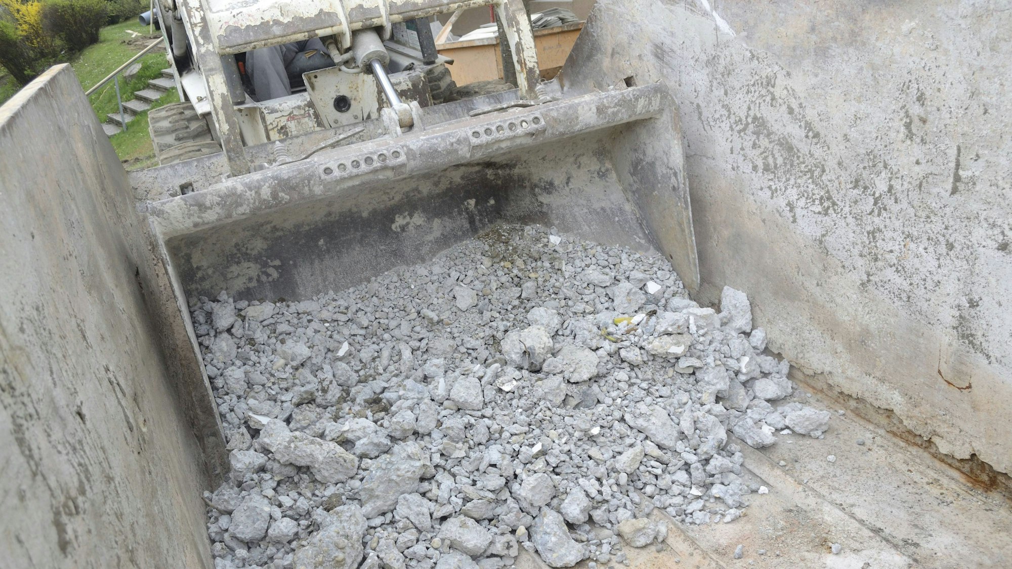 Bauschutt wird von Bagger in Container geschüttet