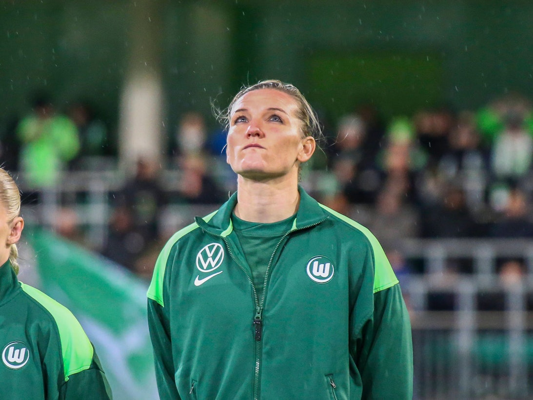 Alex Popp steht vor einem Spiel auf dem Feld und schaut nach oben.