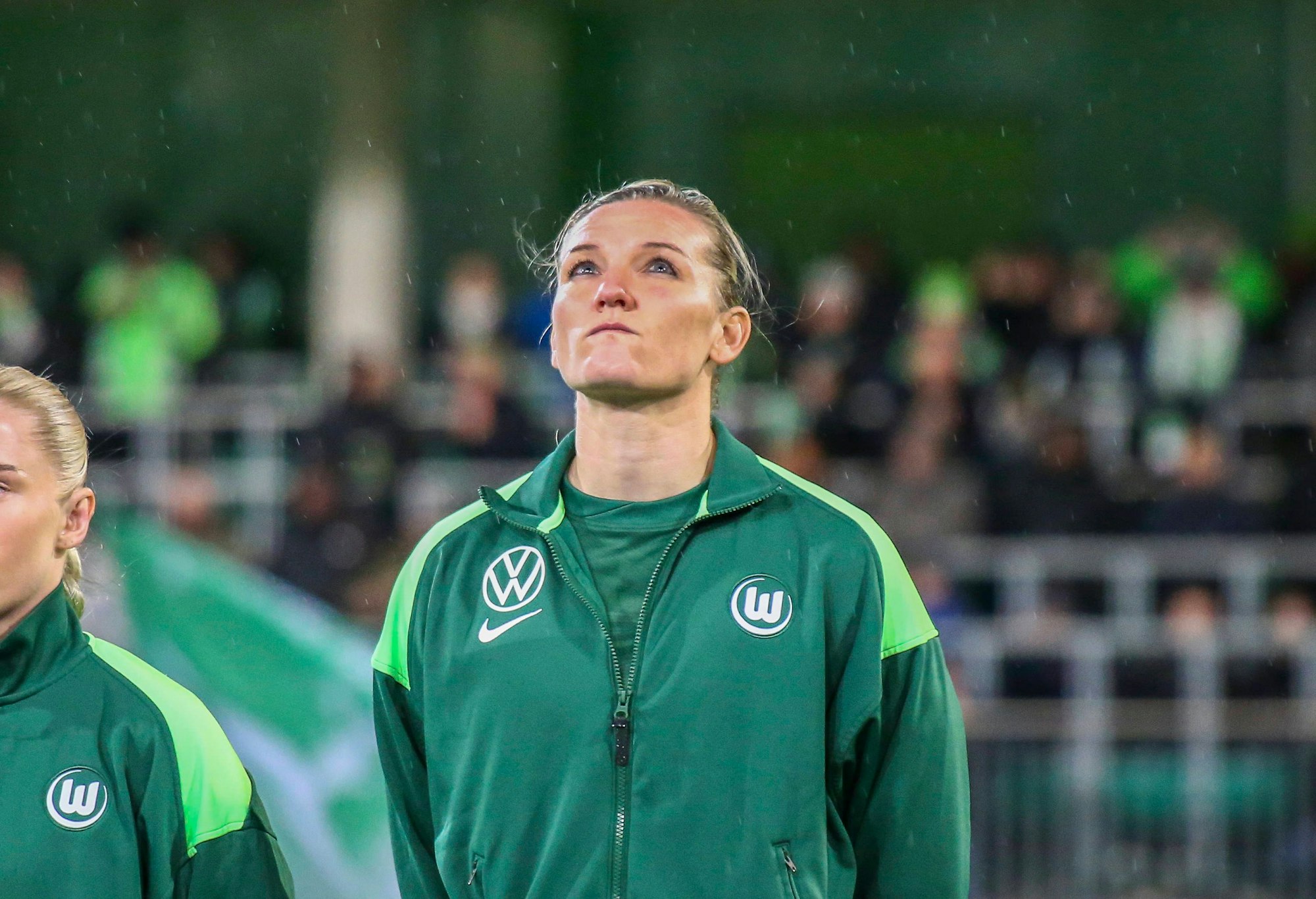 Alex Popp steht vor einem Spiel auf dem Feld und schaut nach oben.