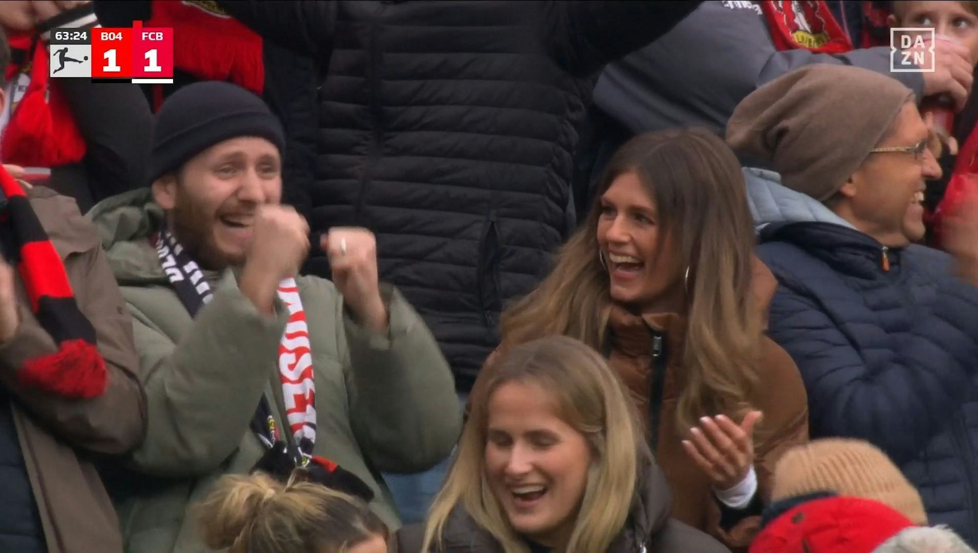 Auf der Tribüne lacht Mara Mones beim Spiel von Bayer Leverkusen.