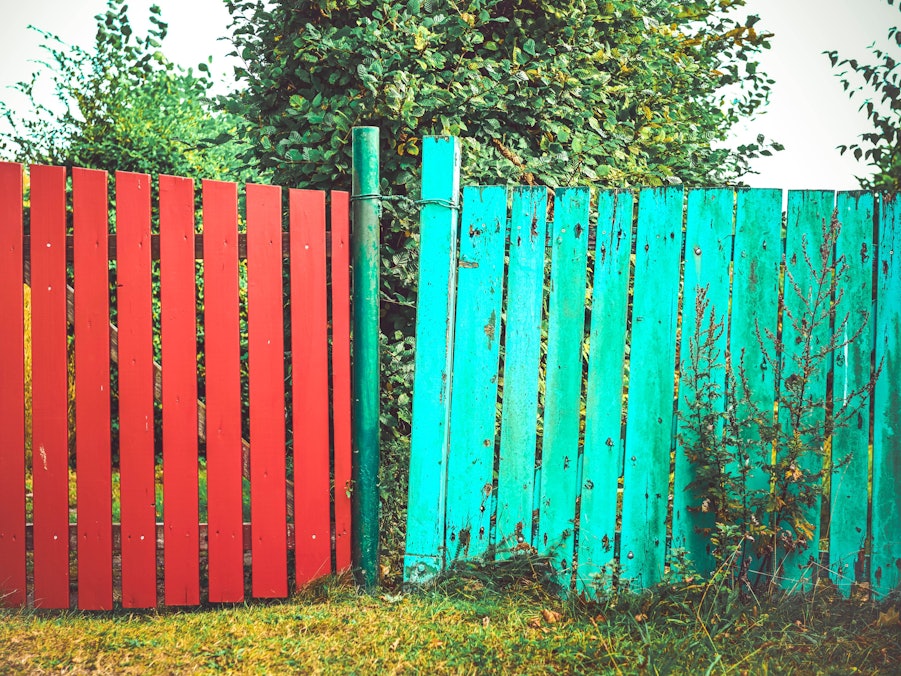 Zwei bunte Zäune, Symbolbild Nachbarschaftsstreit