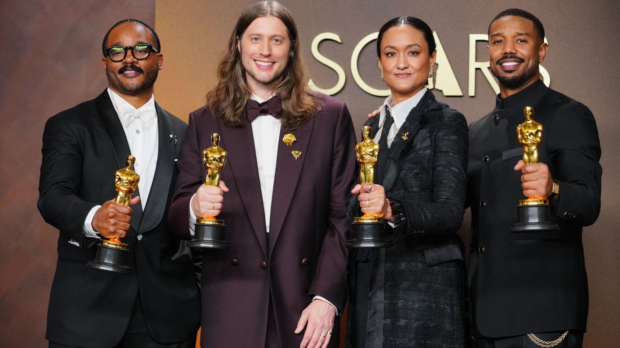 Drei Männer und eine Frau halten ihren Oscar in der Hand.