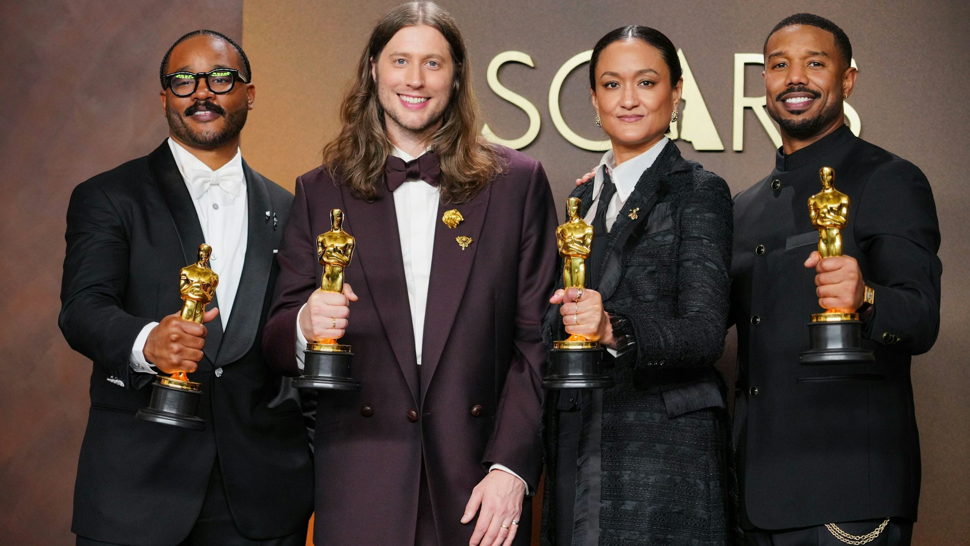 Drei Männer und eine Frau halten ihren Oscar in der Hand.