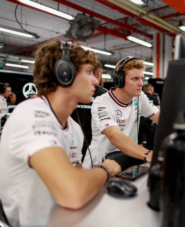 Mick Schumacher und Kimi Antonelli blicken gemeinsam auf einen Bildschirm.