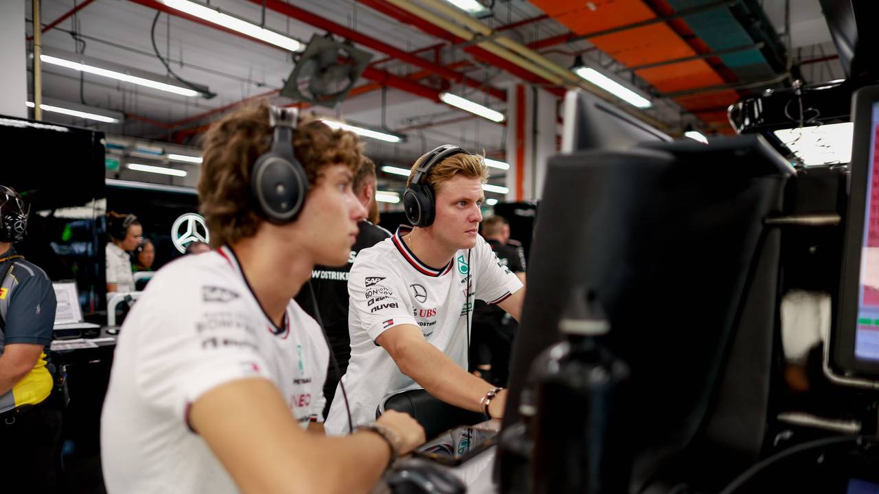 Mick Schumacher und Kimi Antonelli blicken gemeinsam auf einen Bildschirm.