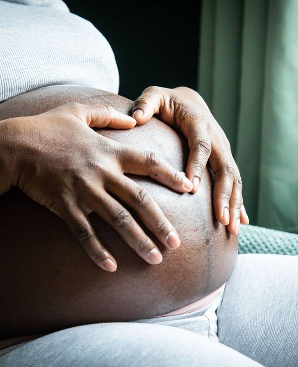 Eine im 9. Monat schwangere Frau sitzt in einem Sessel