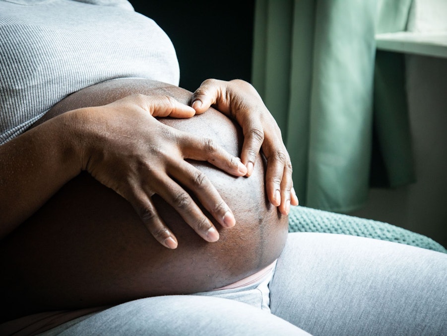 Eine im 9. Monat schwangere Frau sitzt in einem Sessel
