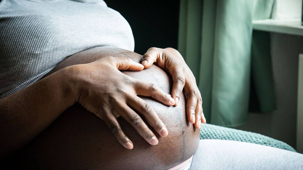 Eine im 9. Monat schwangere Frau sitzt in einem Sessel