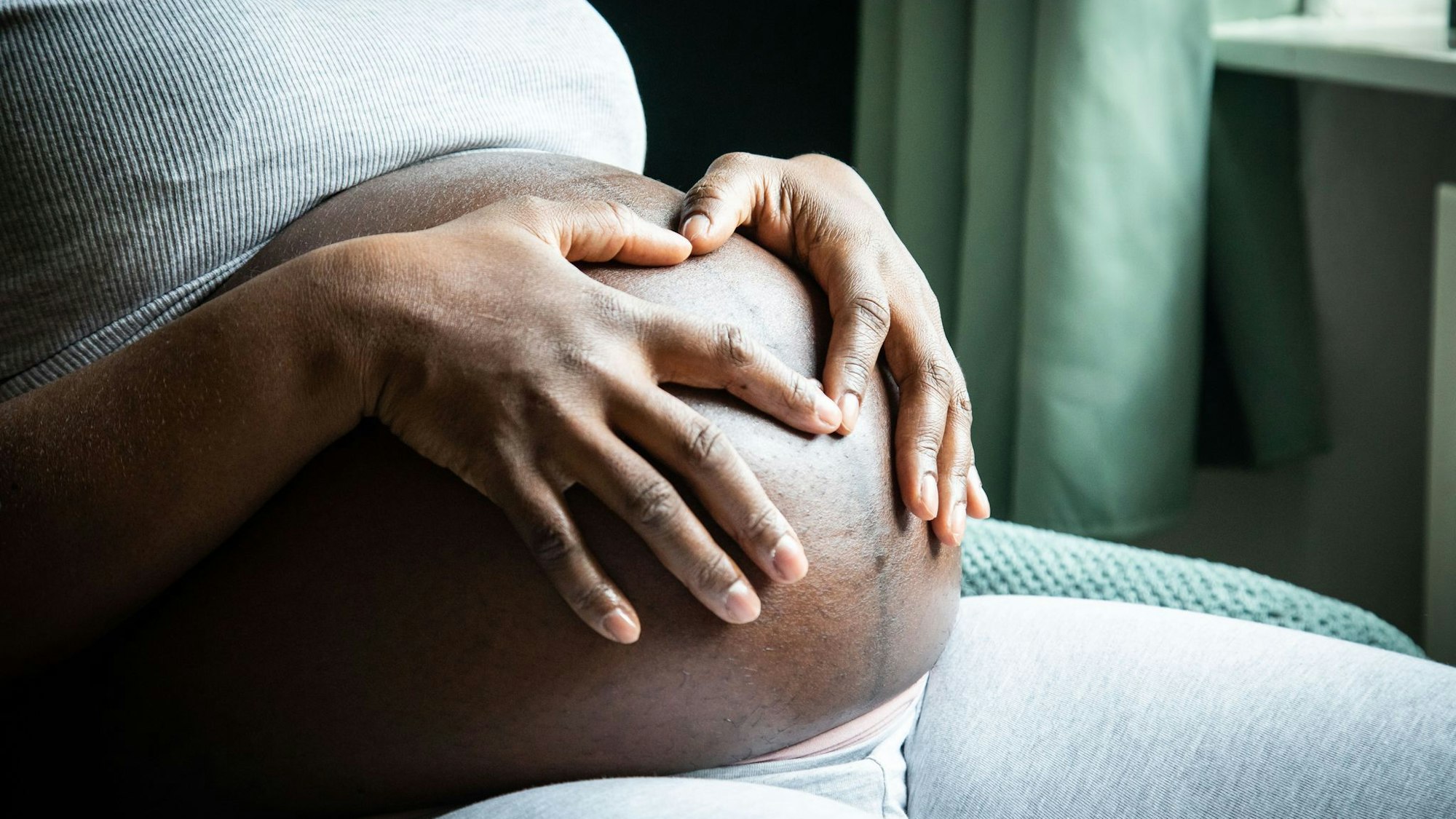 Eine im 9. Monat schwangere Frau sitzt in einem Sessel
