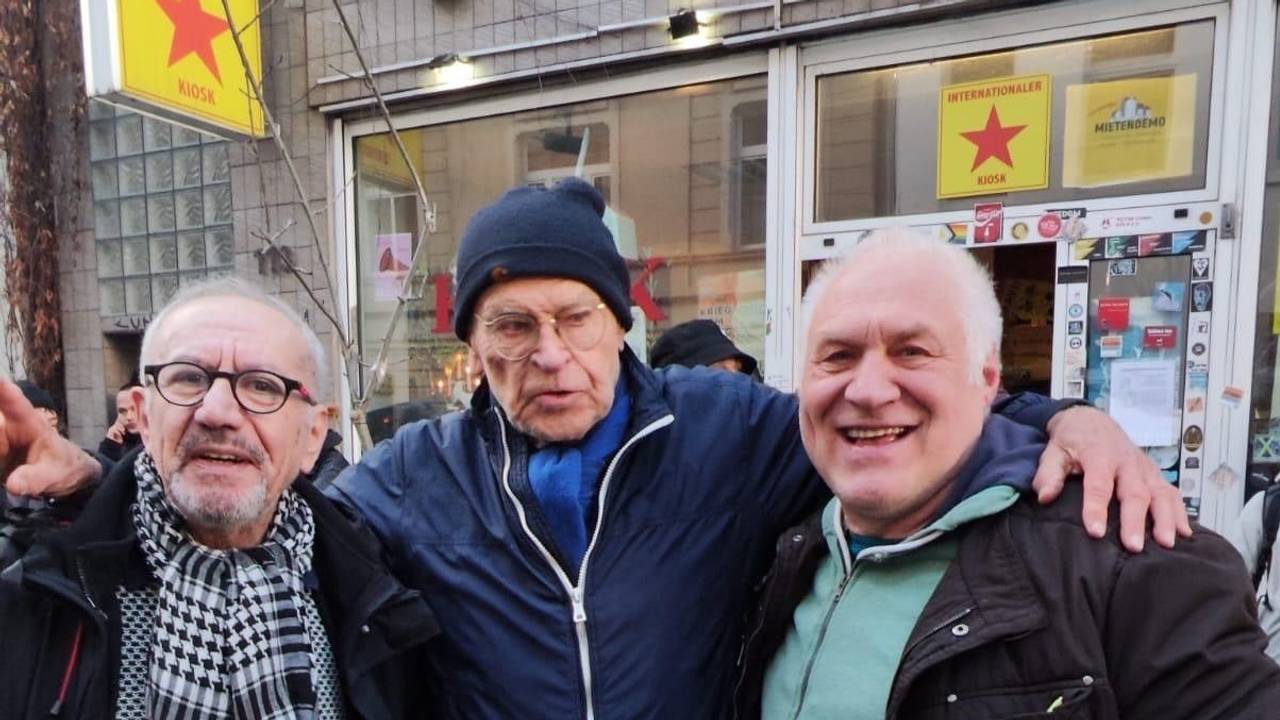 Drei Männer stehen vor einem Kiosk.