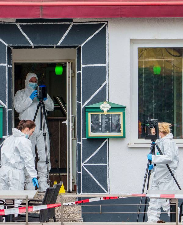 Drei Personen in weißen Schutzanzügen sichern vor sowie in der Tür eines Lokals Spuren.