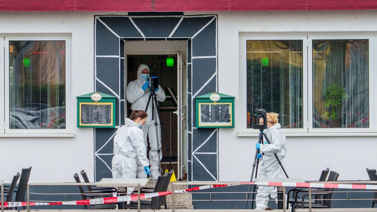 Drei Personen in weißen Schutzanzügen sichern vor sowie in der Tür eines Lokals Spuren.