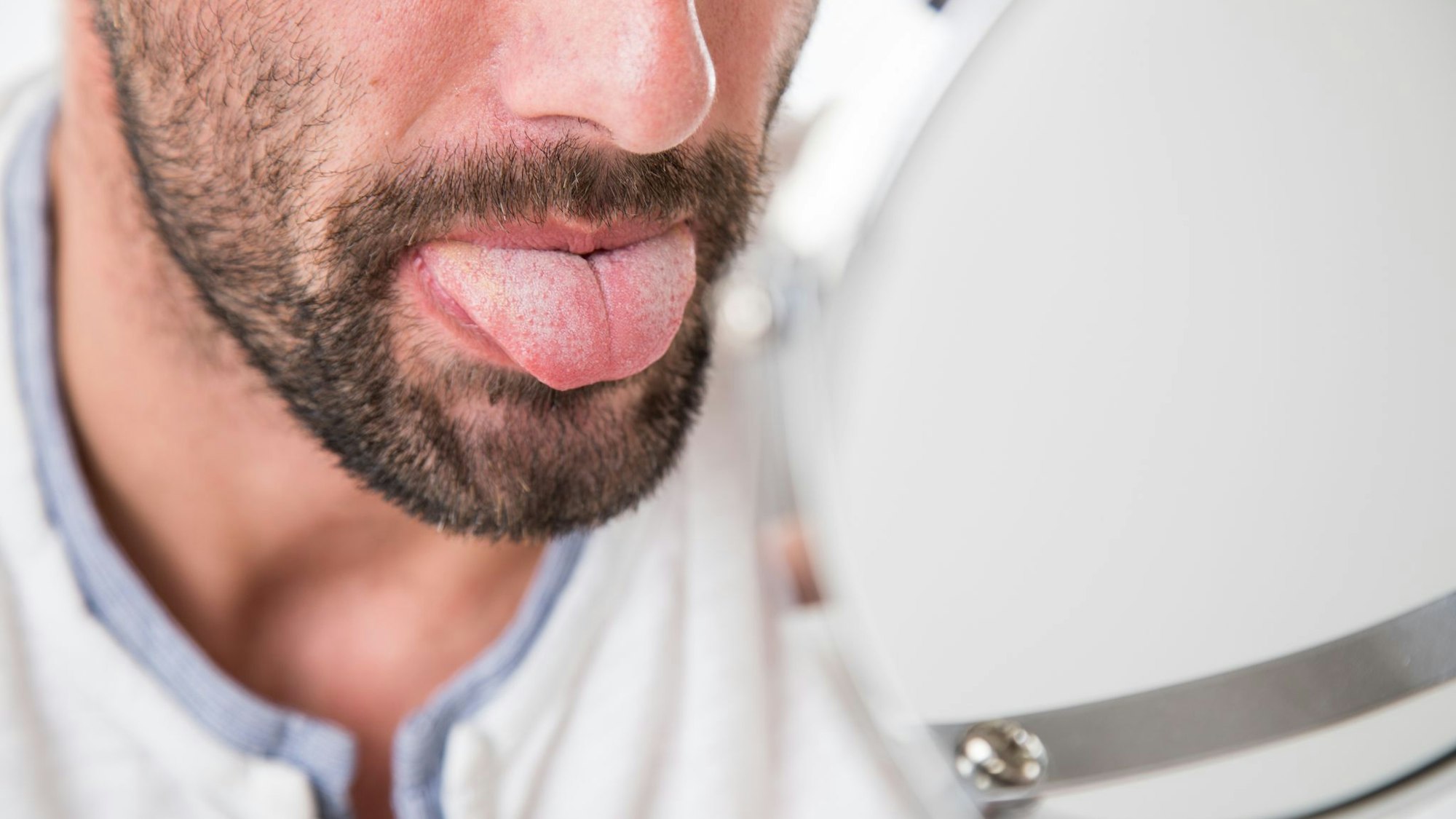Mann betrachtet seine Zunge im Spiegel
