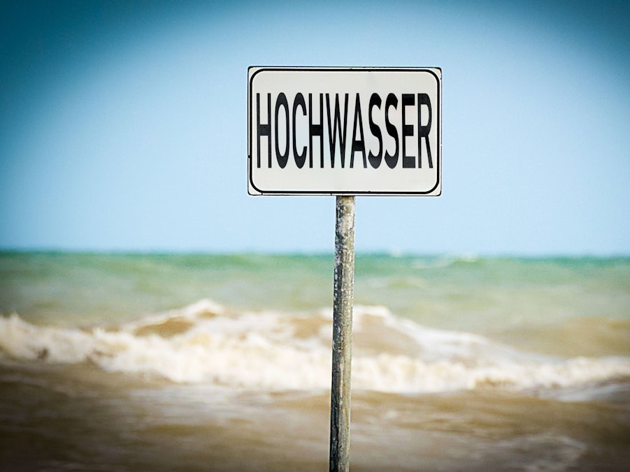 Schild mit „Hochwasser“ vor stürmischem Wasser