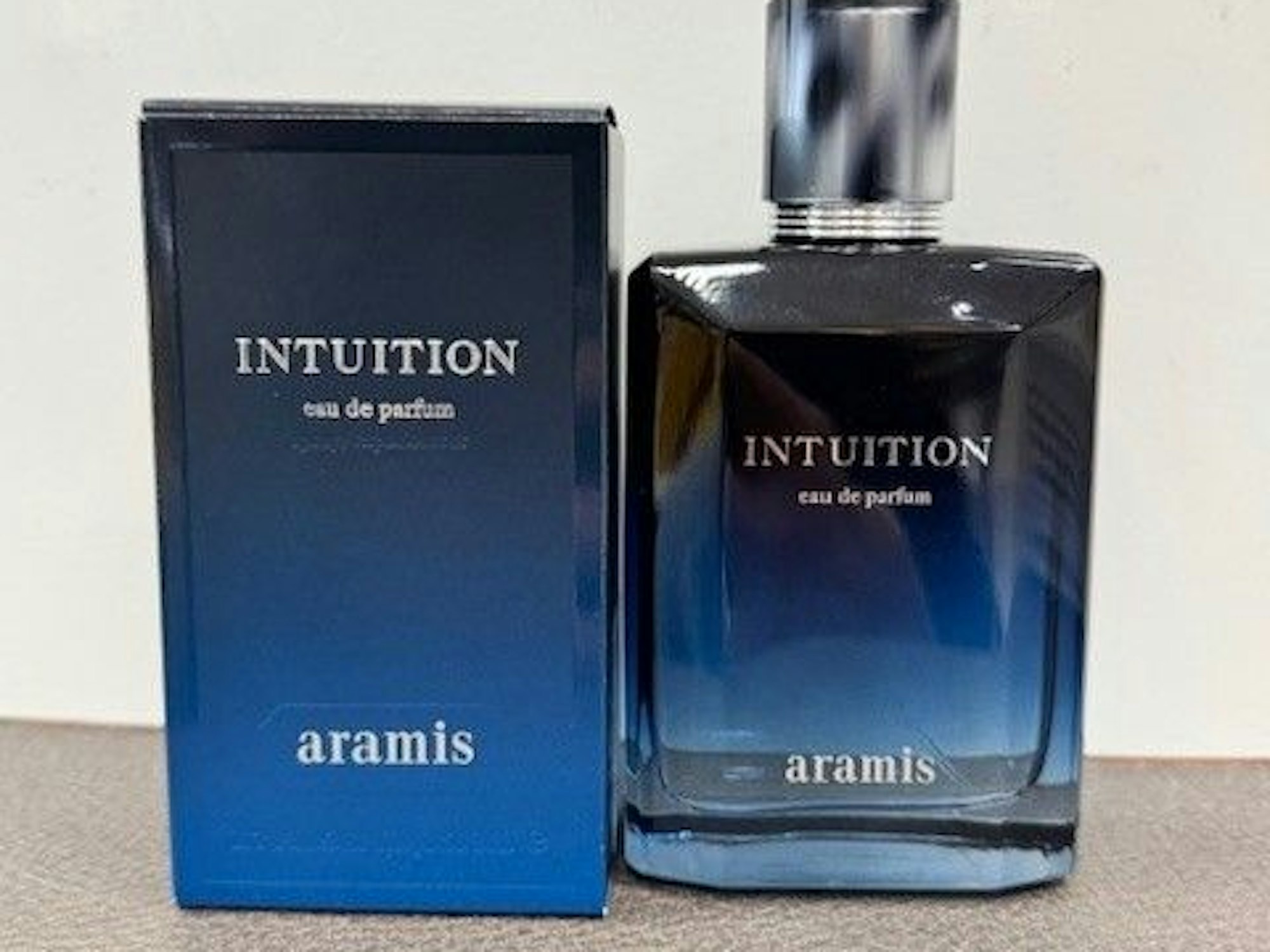 Ein blauer Parfümflakon neben blauer Verpackung