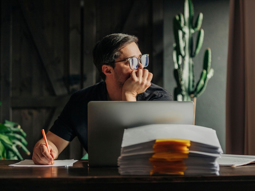 Ein Mann arbeitet am Laptop und sieht aus dem Fenster