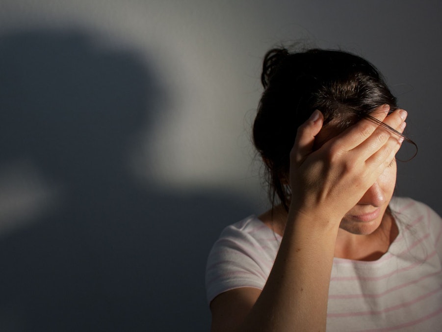 Frau fasst sich an die Stirn