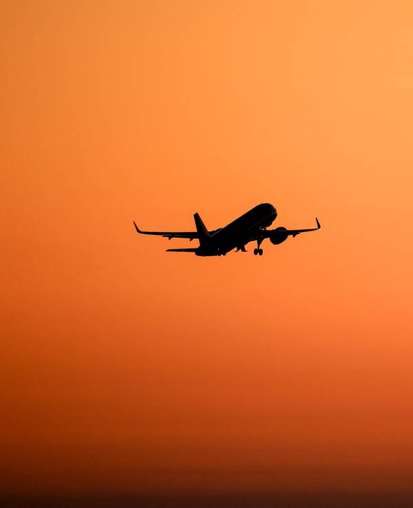 Ein Flugzeug hebt vor orangefarbenem Himmel ab