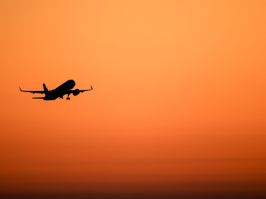 Ein Flugzeug hebt vor orangefarbenem Himmel ab