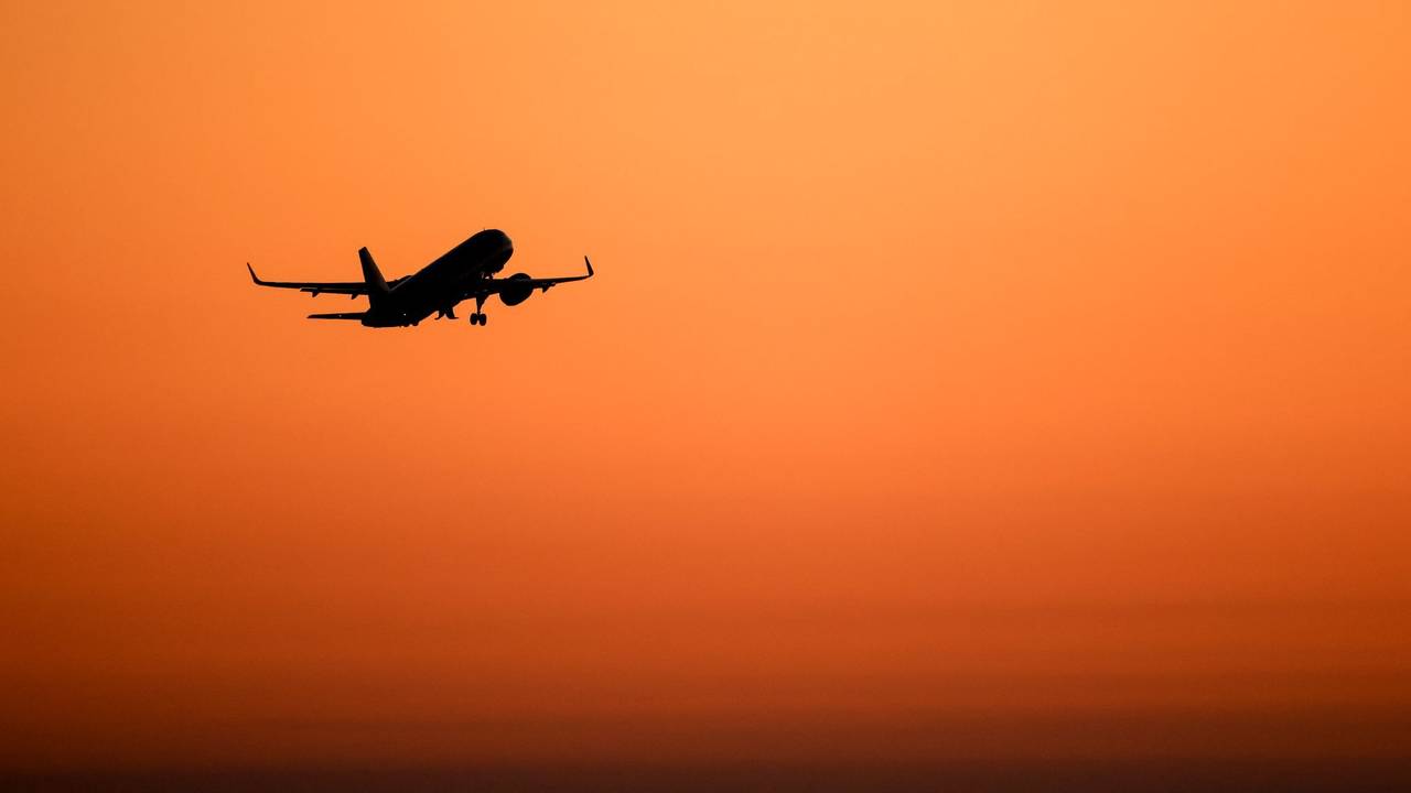 Ein Flugzeug hebt vor orangefarbenem Himmel ab