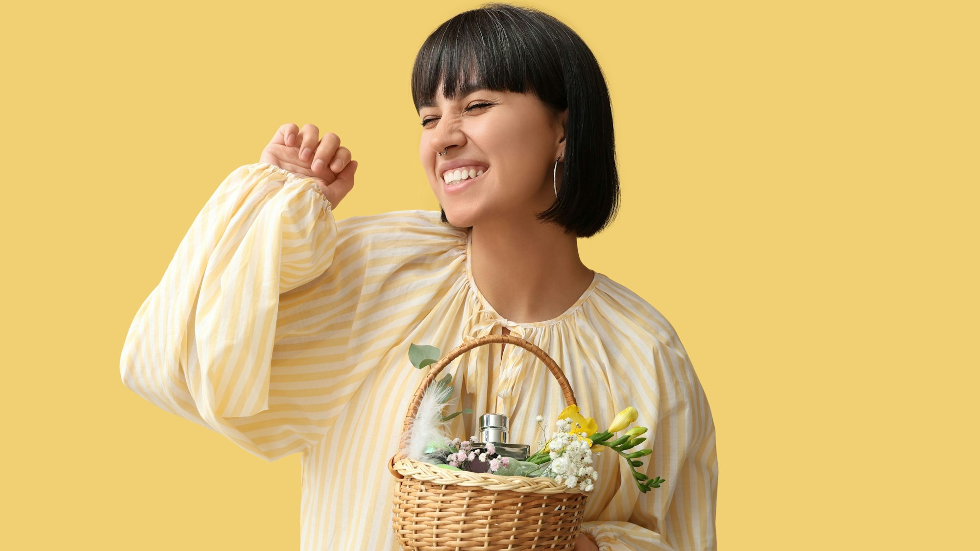 Eine junge Frau hält ein Osterkörbchen mit Parfüm gefüllt.
