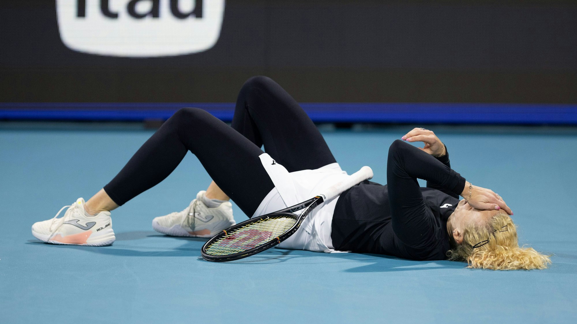 Katerina Siniakova liegt auf dem Rücken und hält sich eine Hand vors Gesicht.