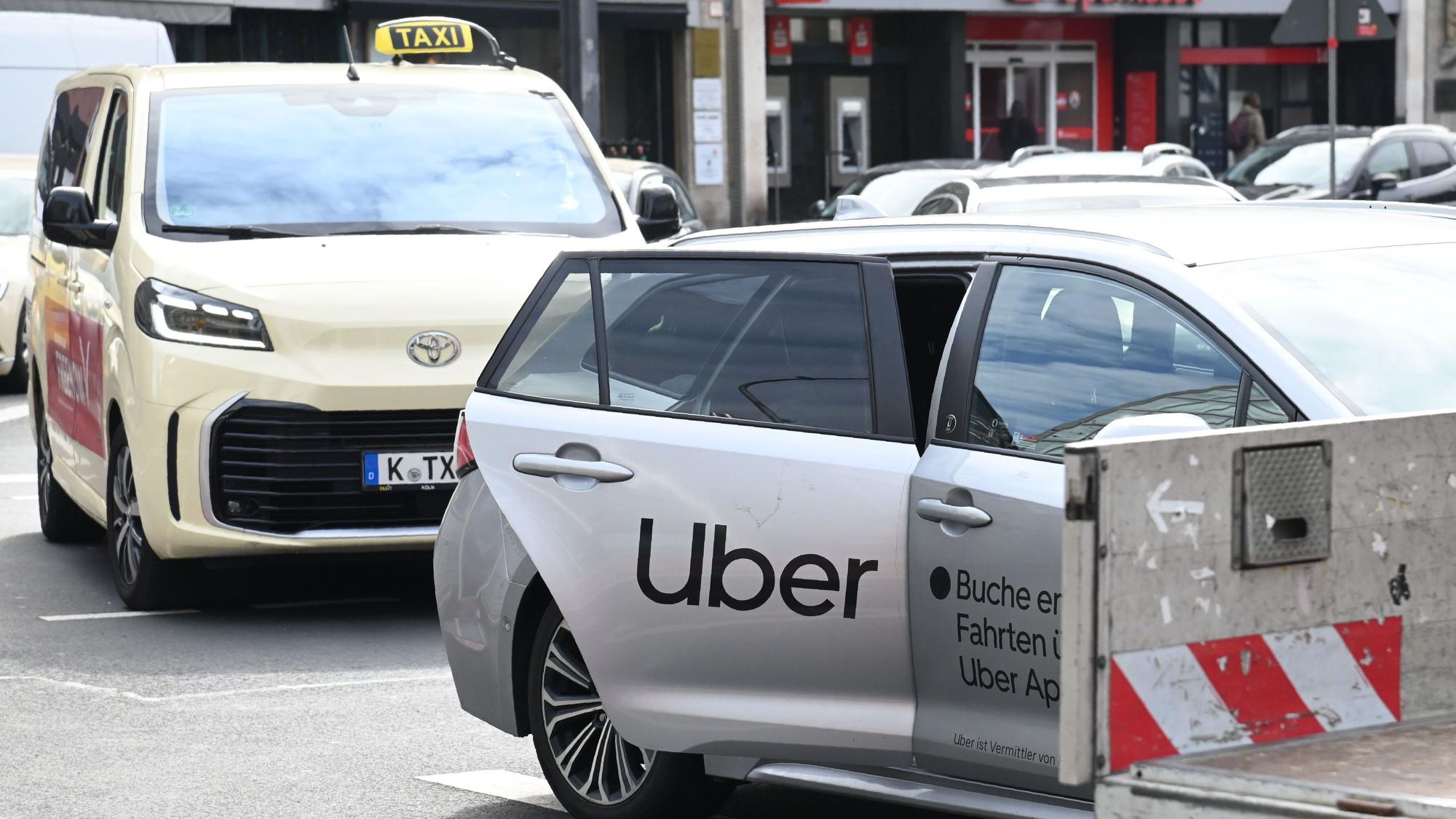 Ein Uber-Fahrzeug parkt vor einem Taxi mit Kölner Kennzeichen.