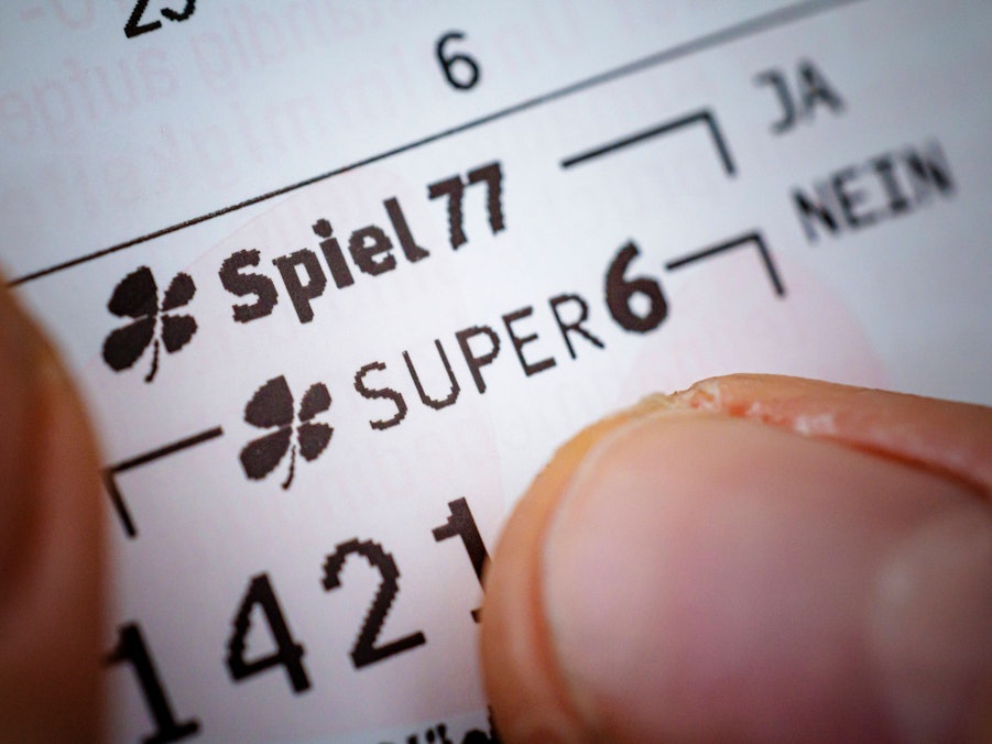 Eine Hand mit Lottoschein „Spiel 77“ und „Super 6“