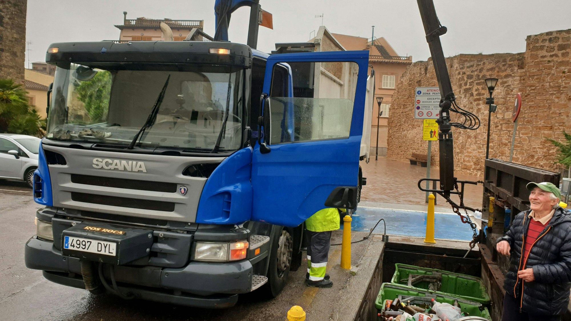 LKW mit Kran und Personen leeren Abfallcontainer