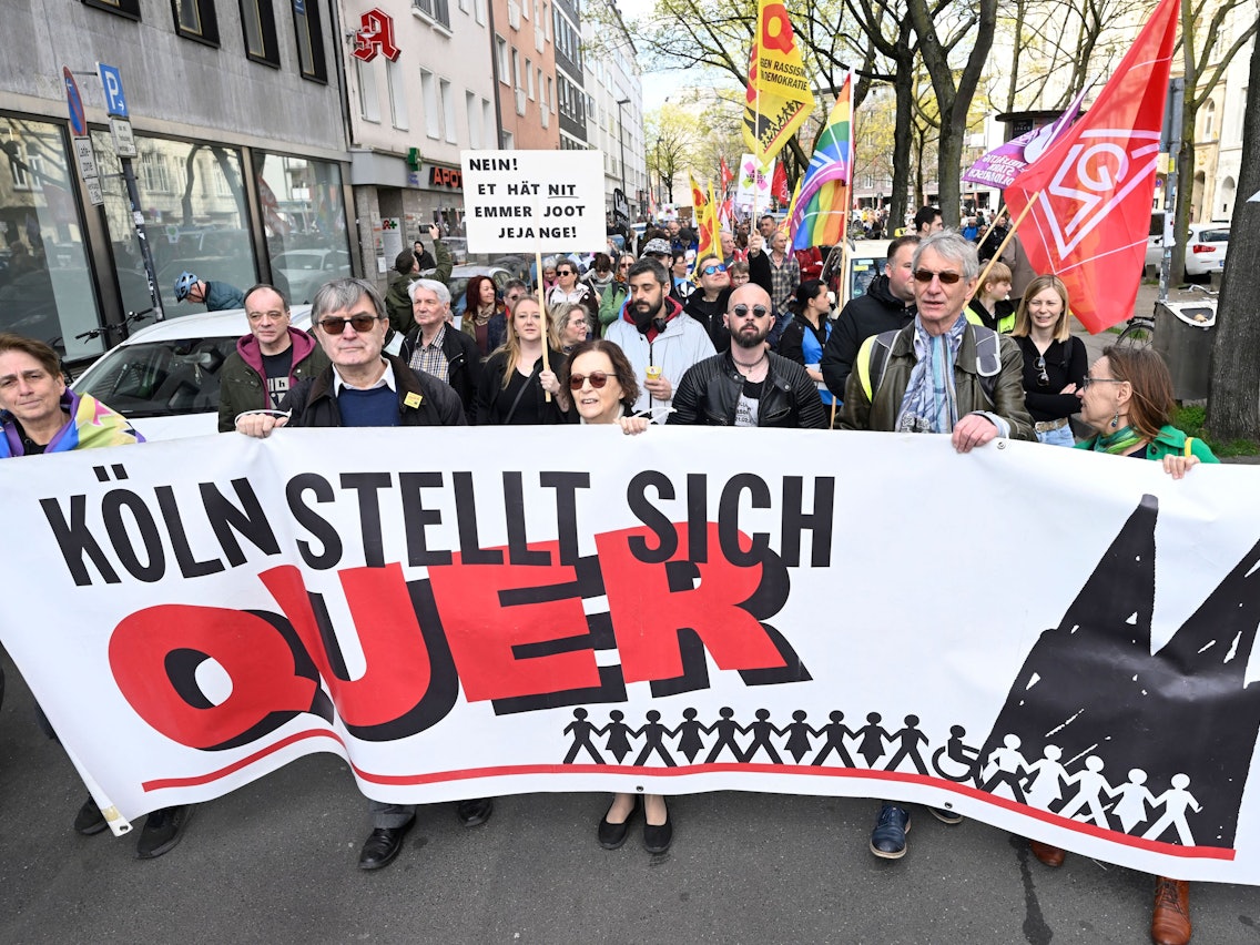 Menschen tragen ein Plakat mit der Aufschrift Köln stellt sich quer.